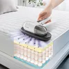 A hand is using a handheld vacuum cleaner on a mattress, with a cutaway showing mites inside the mattress layers. Voir les images du produit