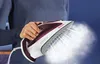 A person is holding a steam iron that is emitting steam. Produktbild-Vorschau
