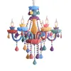 A colorful, whimsical chandelier with multiple arms and hanging decorative elements. Produktbild-Vorschau