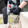 A person wearing black gloves is using a Practixx PX-BH-5 Bohrhammer to break apart a concrete structure. Produktbild-Vorschau
