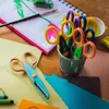 A collection of craft scissors and art supplies laid out on a wooden table. Voir les images du produit