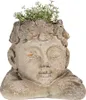 A close-up of a decorative planter shaped like a head, with small white flowers growing out of it. Podgląd zdjęcia produktu