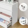 Close-up views of a white dresser with drawers, showing the drawer slides and a metal bracket for wall mounting. Some drawers contain folded clothing. Náhľad obrázku produktu