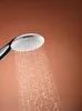 A close-up shot of a shower head with water spraying from it against a brown background. Anteprima dell’immagine prodotto
