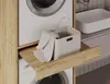 A close-up view of a laundry cabinet with a washing machine and a pull-out shelf holding a laundry basket. Náhled obrázku produktu