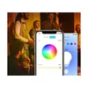 A group of people are gathered, with one person holding a smartphone displaying a smart bulb control app. Produktbild-Vorschau