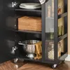 A close-up view of a black kitchen cart with open doors, showcasing its shelves and contents. Produktbild-Vorschau