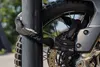 A close-up of a motorcycle chain lock securing a motorcycle wheel to a pole. Anteprima dell’immagine prodotto