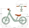 A mint green balance bike with brown accents, shown with dimensions indicated by measurement lines and text. Produktbild-Vorschau