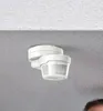 A white motion detector mounted on a ceiling. Produktbild-Vorschau