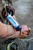 A person is holding a water filter straw and fishing gear near a body of water. Podgląd zdjęcia produktu