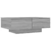 A modern, gray wooden coffee table with two drawers, shown from a side angle against a white background.