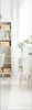 A bright, minimalist room with a white bookshelf and a white cabinet with wooden legs. Produktbild-Vorschau