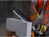 A person wearing a safety vest and gloves is using a DeWalt saw to cut a concrete block. Náhľad obrázku produktu