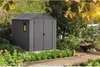 A gray garden shed is shown in a garden setting with plants and a wheelbarrow. Náhled obrázku produktu