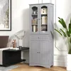 A gray storage cabinet with glass doors and a drawer, placed in a living room setting next to a sofa and a plant. Voir les images du produit
