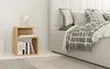 A bedside table with books and a lamp next to a bed with pillows and a blanket. Podgląd zdjęcia produktu