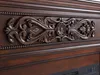 A close-up view of ornate wooden carving on a dark brown piece of furniture. Podgląd zdjęcia produktu