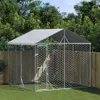 An outdoor dog kennel with a roof, set up on a grassy lawn with trees and a wooden fence in the background. Voir les images du produit