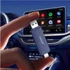 A hand holding a Carlinkit adapter in front of a car's infotainment screen. Produktbild-Vorschau