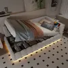 A daybed with storage, dressed with bedding and throws, in a room setting with a patterned rug and wall art. Voir les images du produit