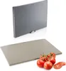 Two cutting boards are shown, one above the other. The top cutting board is silver and has a holder. The bottom cutting board is beige and has tomatoes on it. Anteprima dell’immagine prodotto