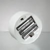 The underside of a white cylindrical object showing a battery compartment with four AA batteries installed. Produktbild-Vorschau