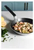 A frying pan filled with cooked shrimp and garnished with parsley and lemon slices, placed on a marble countertop with lemons and parsley in the background. Podgląd zdjęcia produktu