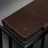 A close-up shot of a dark brown leather phone case with a bull logo embossed on it. Anteprima dell’immagine prodotto