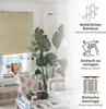A living room scene with a bamboo roller blind, plants, and furniture, featuring marketing text and icons. Voir les images du produit