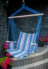 A blue striped hammock chair with wooden armrests hangs in front of a dark stone wall, with potted pink flowers on either side. Anteprima dell’immagine prodotto