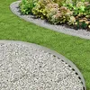 A garden setting showing metal edging separating a lawn from a gravel path and a flower bed. Produktbild-Vorschau