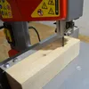 A close-up of a bandsaw cutting a piece of wood. Produktbild-Vorschau