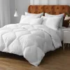 A white comforter is neatly arranged on a bed with a tufted headboard. Produktbild-Vorschau