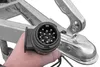 A hand holding a trailer connector plug in front of a trailer hitch. Produktbild-Vorschau