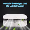 A white air purifier with light rays emanating from it, suggesting air purification, with green leaves floating around. Produktbild-Vorschau