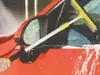 A person is washing a red car, using a squeegee with a telescopic handle to clean the window. Podgląd zdjęcia produktu