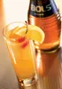 A cocktail with a bottle of Bols Apricot Brandy in the background. Produktbild-Vorschau
