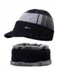 A black knitted winter hat with a visor and a matching neck warmer, both lined with gray faux fur, are displayed against a white background. Produktbild-Vorschau