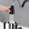 A hand is holding a black kitchen faucet spray head over a stainless steel pot, with water flowing from the spray head into the pot. Produktbild-Vorschau