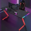A gaming desk setup with a monitor, laptop, and gaming chair, illuminated by RGB lighting. Produktbild-Vorschau