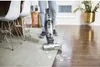 A person is using a BISSELL CrossWave Hydrosteam vacuum cleaner on a carpet and hardwood floor. Voir les images du produit
