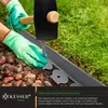A person wearing green gloves is using a hammer to install a garden edging stake into the ground next to a gravel path and grass. Produktbild-Vorschau