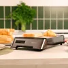 A toaster with bread and a croissant on a kitchen counter. Produktbild-Vorschau