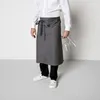 A person wearing a white shirt and a grey apron, holding two wine glasses. Produktbild-Vorschau