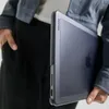 A person holding a MacBook Pro in a protective case. Produktbild-Vorschau