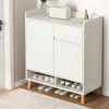 A white shoe cabinet with wooden legs, filled with shoes. Náhľad obrázku produktu