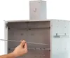 A hand is shown inserting a metal rod into a silver smoking oven. Náhled obrázku produktu