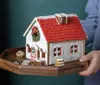 A gingerbread house decorated for Christmas, placed on a wooden tray, held by a person. Náhľad obrázku produktu