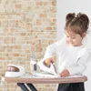 A young girl is playing with a toy ironing board and iron. Produktbild-Vorschau